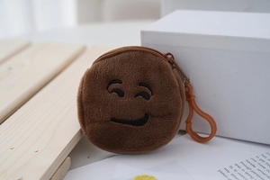 Detailed view of a round brown plush emoji coin purse with a smiling face embroidery