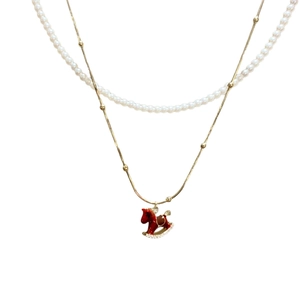Gold-plated layered pearl necklace featuring a vibrant red enamel rocking horse pendant