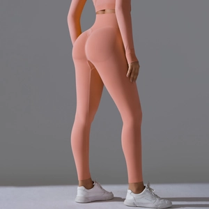 Close-up of seamless scrunch butt leggings and long sleeve crop top in peach orange