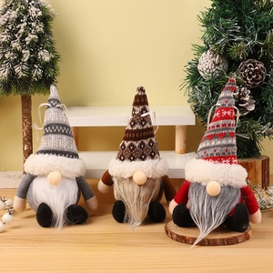 Three Christmas gnome plush ornaments with knitted hats and faux fur beards on wood