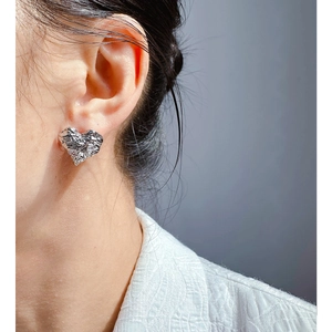 Silver heart earrings with textured foil pattern and zircon accents on model