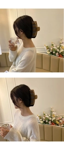 Detail of a large brown matte shark hair clip showing hair styling effect on a model