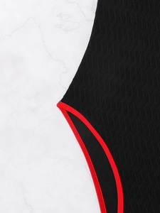 Detailed macro view of black textured swimsuit fabric with contrast red piping edge