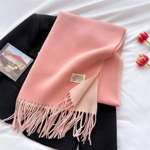 Detail of pink and beige cashmere-like scarf with fringe on a black coat with tulips