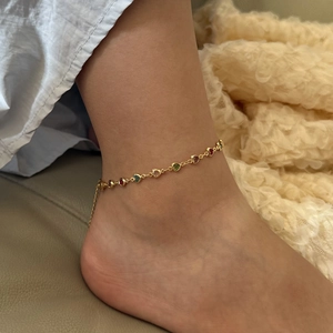 Chic gold anklet with colorful rhinestones and heart charms on woman's ankle