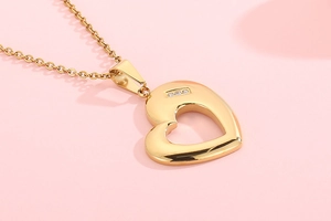 Detail view of a hollow heart-shaped gold pendant with sparkling inlaid rhinestones