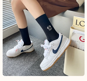 Close-up of black knitted socks featuring cute puppy embroidery with blue sport sneakers
