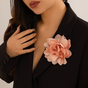 Detailed view of a light pink layered fabric flower brooch on a black blazer jacket