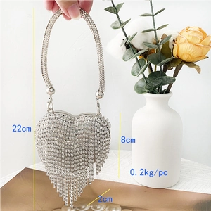 Close-up of silver heart-shaped evening bag with crystals and tassel showing dimensions