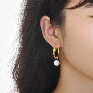 Close-up of vintage golden knot hoop earrings with elegant white hanging pearls