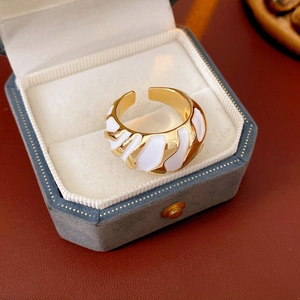 Detailed view of vintage gold-tone twist open ring with white enamel in a jewelry box