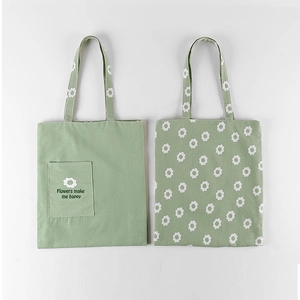 Detail of light green canvas tote bags featuring small white daisies and floral slogans