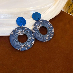Detail of round blue earrings featuring white plum blossoms and elegant tassels