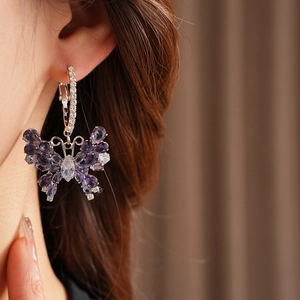 Detail of butterfly drop earring with purple zircon stones worn by a model