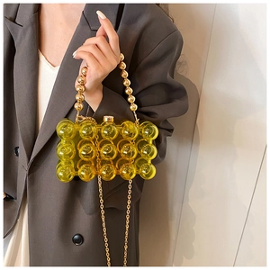 Detail view of yellow acrylic bubble handbag with pearl handle and gold chain strap