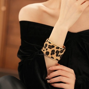 Luxurious wide leopard print cuff bracelet with golden metal trim on female wrist