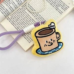 Close-up of yellow plush coffee cup charm with embroidered face and pearl strap details
