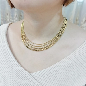 Detail of layered gold ball chain necklaces showing elegant stacked bead design for women