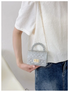 Detail of transparent glitter jelly bag with beaded handle and golden twist lock