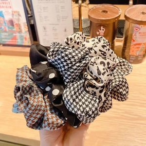 Close-up of assorted scrunchies with polka dots, houndstooth, and animal prints in hand
