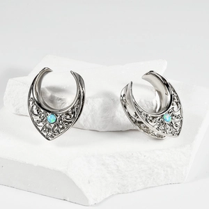 Saddle ear plugs in stainless steel with hollow patterns and blue synthetic opal stones
