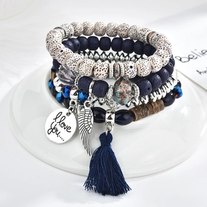 Detail of multi-layered beaded bracelet with wing charm, blue tassel and love tag
