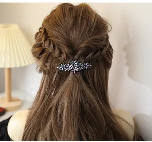 Detail of elegant floral hair clip with purple rhinestones on wavy brown hair