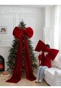Detailed view of giant wine red velvet Christmas bow hanging on a classic fireplace mantel