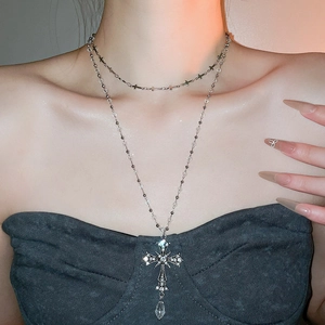 Detail of layered silver cross pendant necklace with sparkling crystals on model