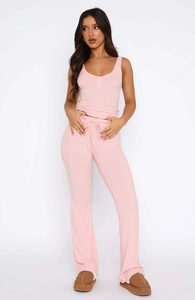 Detail view of pink ribbed knit set featuring V-neck buttoned vest and flared trousers