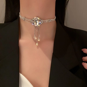 Détail d'un collier ras du cou vintage argenté avec strass et glands en cristal sur modèle
