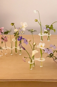 Macro view of creative glass tube vases with wave-shaped white stands on a wooden desk