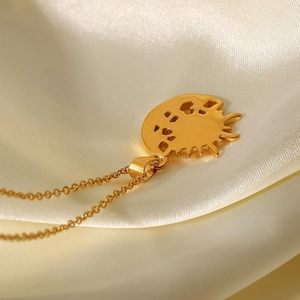 Close-up of 18k gold plated sun pendant necklace on elegant white satin fabric