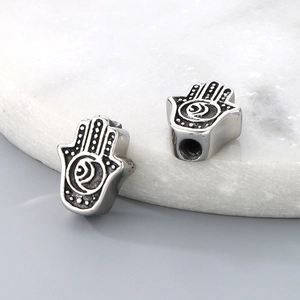 Macro shot of silver Hamsa hand beads with vintage patterns for DIY bracelet jewelry