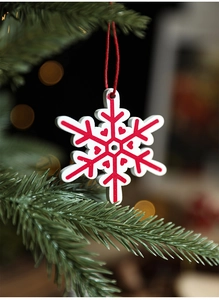 Detailed view of red and white wooden snowflake ornament hanging on a Christmas tree