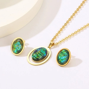 Detail view of gold-plated titanium necklace and green resin earrings set on white podium