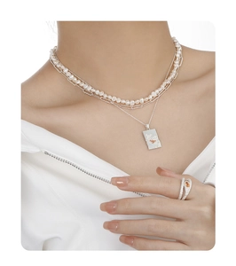 Detail of layered pearl and silver necklace with orange gemstone pendant and matching ring