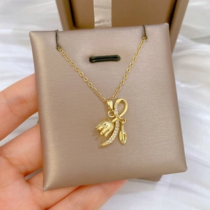 Close-up of golden tulip flower pendant necklace with shimmering crystals on a satin pad