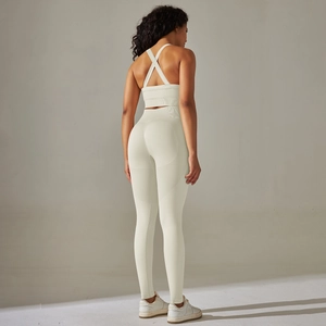 Detail of cross-back sports bra and high-waisted leggings in creamy white knit fabric
