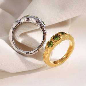 Macro detail of 18K gold and silver stainless steel rings with three green zircons