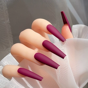 Vue macro détaillée de longs faux ongles ballerine bordeaux mats à texture veloutée