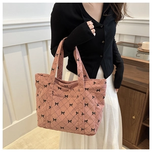Detailed texture of pink corduroy tote bag featuring a black bow pattern and sturdy handles