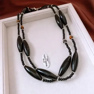 Detailed view of tiered necklace with tiger eye beads and black polished glass stones