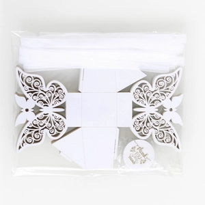 Flat lay of laser-cut butterfly gift box with white ribbon and thank you tag components