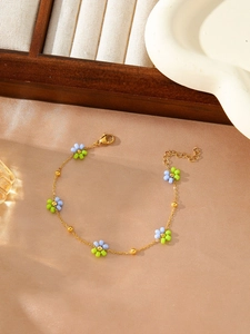 Detailed macro view of gold-plated flower bracelet with blue beads on silk background