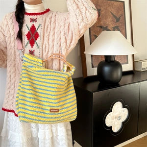 Detailed view of striped plush tote bag with rope handles and pink shoulder strap