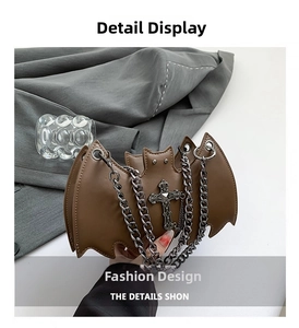 Detail of bat-shaped leather bag with vintage metal cross and chunky grey chain