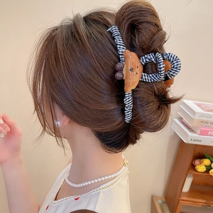 Détail d'une pince à cheveux en forme de croissant marron sur un chignon élégant
