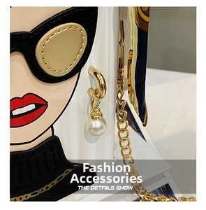 Detail of white evening bag featuring fashion illustration, pearl charm and gold chain strap