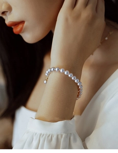 Detailed view of pink pearl bracelet with adjustable gold chain on wrist